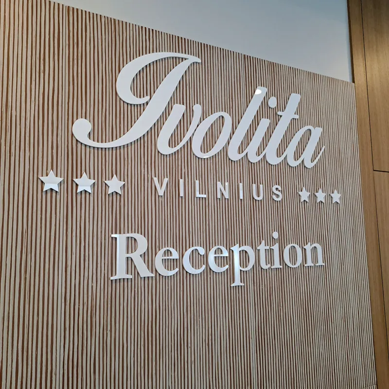 Lazeriu pjauta viešbučio registratūros iškaba su logotipu ant medinės sienos